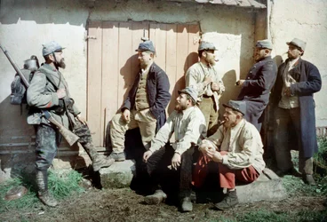 Zeven Franse soldaten voor een gebouw, een draagt zijn geweer en uitrusting, Frankrijk, ca. 1914-18